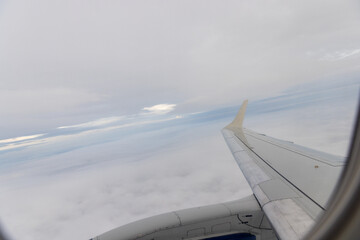 Fototapeta na wymiar view of jet plane wing on the background of thick clouds and blue sky