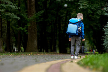 Little boy with backpack going to school. Rear view. First grader