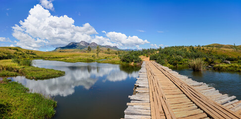 River flowing under wooden bridge near Sendrisoa as seen during trek to Andringitra national park in Madagascar, mountains visible at distance
