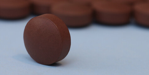 One pill on a blurred background of many pills.