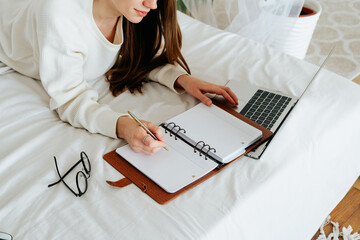 Distance learning online education and work. Business woman writes to do list in notebook. Cropped...