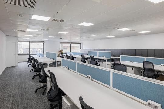Spacious gray office with long tables and chairs in front of the opening of the training and seminar center waiting for the students. Concept of commercial spaces in the city center