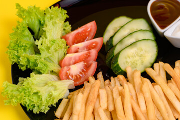 Plate of french fries with lettuce, tomatoes and cucumbers, sauces in white french fries plates.