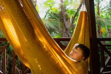 child sleeping in a yellow hammock on vacation