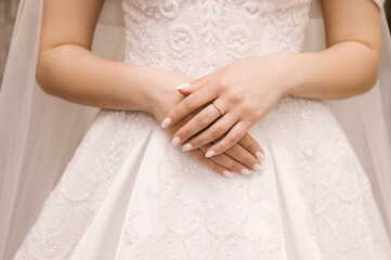 Obraz na płótnie Canvas The bride's hands with a beautiful manicure and a diamond ring