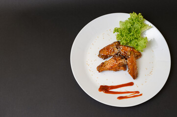 Caramelized chicken wings on a plate with salad and barbecue sauce