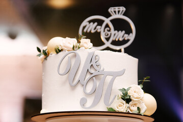 White wedding cake with flowers and initials of the newlyweds