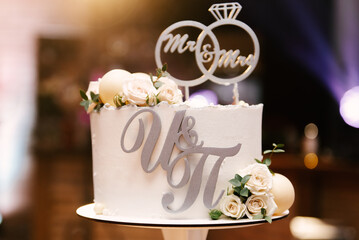 White wedding cake with flowers and initials of the newlyweds