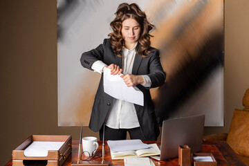 A beautiful businesswoman, formally dressed, tears up papers. unsuccessful business. breaking contract document.
