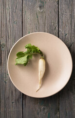 one long white radish on a beige plate