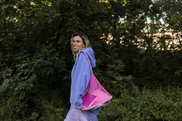 Portrait of beautiful confident woman laughing in nature, walk in park and look at camera. Blonde curly woman look happy, enjoy of nature, amazement woman in purple hoody smiling.