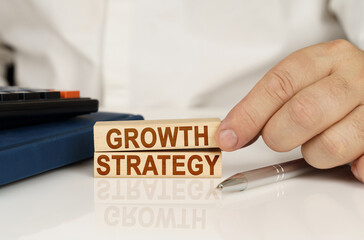 In the hands of a businessman, wooden blocks with the inscription - Growth Strategy