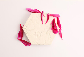 Purple pion flowert petal and stones platform podium on beige background. Minimal empty display product presentation scene. Flat lay, top view.