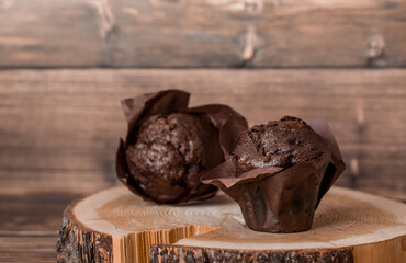 Delicious freshly baked chocolate muffins on a wooden background. Delicious cupcake close-up. The context of a bakery with pastries. Confectionery products.