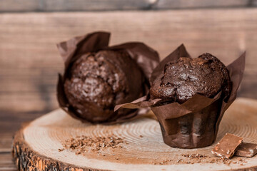 Delicious freshly baked chocolate muffins on a wooden background. Delicious cupcake close-up. The context of a bakery with pastries. Confectionery products.