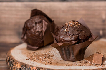 Delicious freshly baked chocolate muffins on a wooden background. Delicious cupcake close-up. The context of a bakery with pastries. Confectionery products.