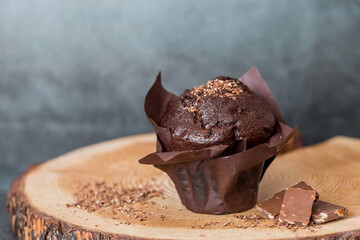 Delicious freshly baked chocolate muffins on a dark background. Delicious cupcake close-up. The context of a bakery with pastries. Confectionery products.