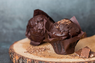 Delicious freshly baked chocolate muffins on a dark background. Delicious cupcake close-up. The context of a bakery with pastries. Confectionery products.