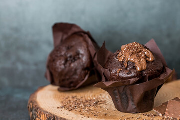 Delicious freshly baked chocolate muffins on a dark background. Delicious cupcake close-up. The context of a bakery with pastries. Confectionery products.