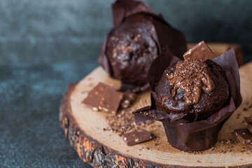 Delicious freshly baked chocolate muffins on a dark background. Delicious cupcake close-up. The context of a bakery with pastries. Confectionery products.