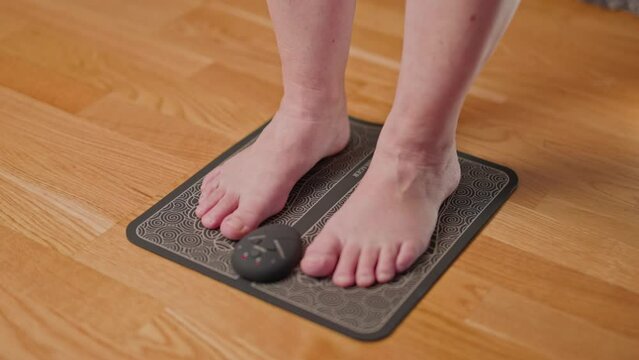 Close up view of women's legs using ems foot massager pad. Acupuncture simulator for home use. Sweden. 