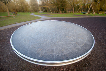 Close up of fun metal roundabout disc in children's outdoor playground. Modern design, urban park. 