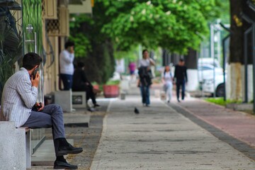 A man on a scientific bench is talking on a mobile phone. White jacket and black shoes. No face.