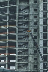 The concrete building is unfinished. You can see the spans between the floors and the stairs. A crane boom is visible from the side. 