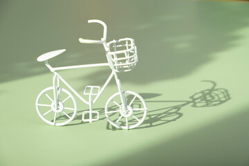 Fototapeta na wymiar Decorative white bycicle on green background with hard shadows. Sustainable lifestyle concept
