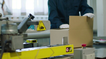 Closing a cardboard box on a conveyor belt line. Distribution warehouse. Concept of e-commerce service, storage, delivery and packaging.