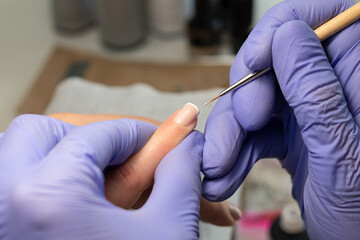 Fototapeta na wymiar The process of creating a French manicure. Manicurist draws a white stripe on the nail. Gel polish coating