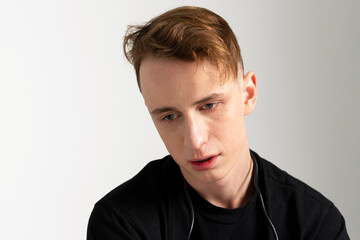 A young man addicted to modern gadgets and technology, looking with a lost gaze. Device dependency. Technological immersion. Isolated on white background.