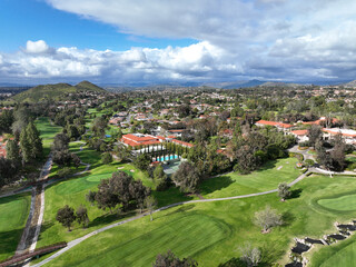 Aerial view of residential neighborhood surrounded by golf and valley during cloudy day in Rancho...