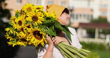 Bouquet of yellow sunflowers in hands of a smiling women outdoor. Patriotic gift with love, gratitude. Mothers Day. Support for Ukraine. Independence Day. High quality 4k video footage - Powered by Adobe