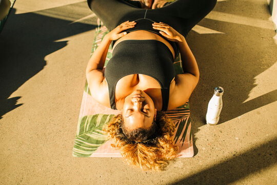 High angle view of woman exercising while lying on floor during yoga class