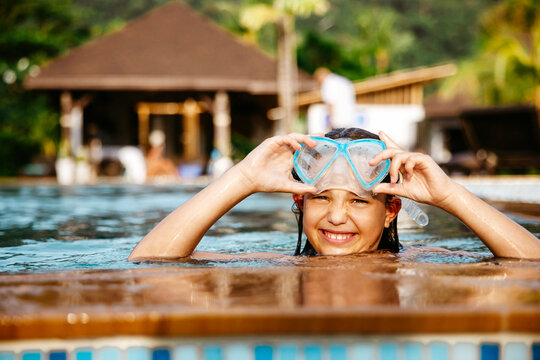 Portrait of smiling girl with swimming googles in pool at resort
