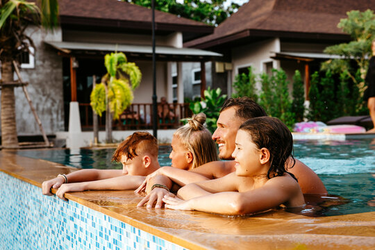 Parents with children in swimming pool at tourist resort during vacation