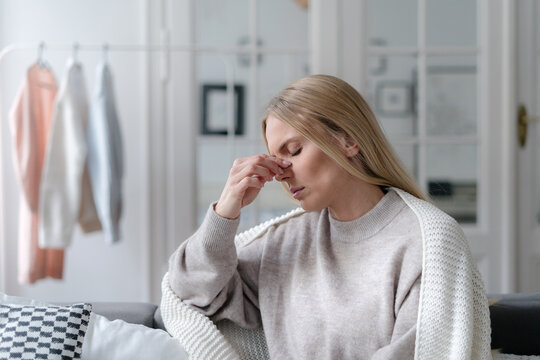 young female suffering from sinus infection, staying sick at home