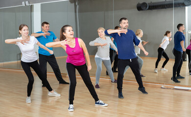 Fototapeta na wymiar Portrait of dancing people practicing vigorous swing during group training in dance studio