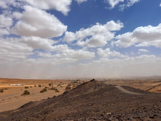 Merzouga, Morocco, Africa, panoramic road in the Sahara desert with view of the beautiful sand dunes, palm trees and tented camps, 4x4 trip, blue sky and white clouds