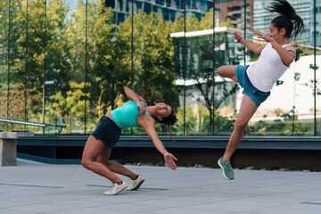 mujeres practicando patadas, ejercicios y capoeira en la ciudad. entre edificios con reflejos en un...
