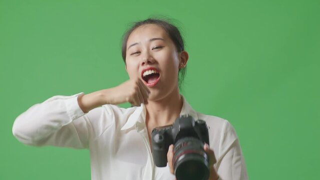 Close Up Of Asian Photographer Looking At The Pictures In The Camera Then Screaming Goal And Dancing To Celebrate Satisfied With The Result While Standing On Green Screen Background In The Studio

