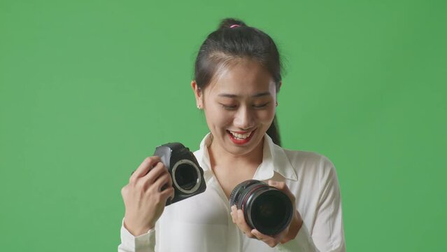 Close Up Of Asian Photographer Changing Lens Of Camera Before Using It Taking Pictures While Standing On Green Screen Background In The Studio

