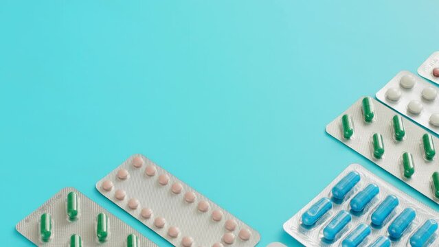 Close-up of a woman's hands lays out pills blasters on a blue background