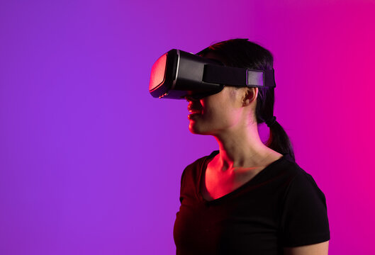 Happy asian woman using vr headset in studio with purple light and copy space