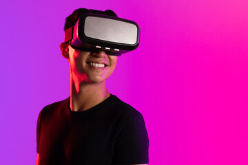 Happy asian man using vr headset in studio with purple light with copy space