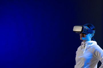 Happy asian woman using vr headset in studio with blue light with copy space