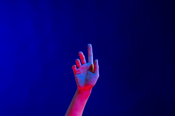 Exposed hand pointing finger in studio with blue light with copy space