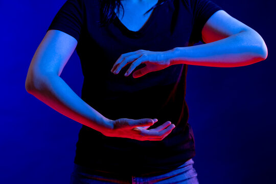 Asian woman making gestures with hands in studio with blue light with copy space - Powered by Adobe
