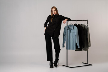Girl in black shirt and black pants next to the clothes rack